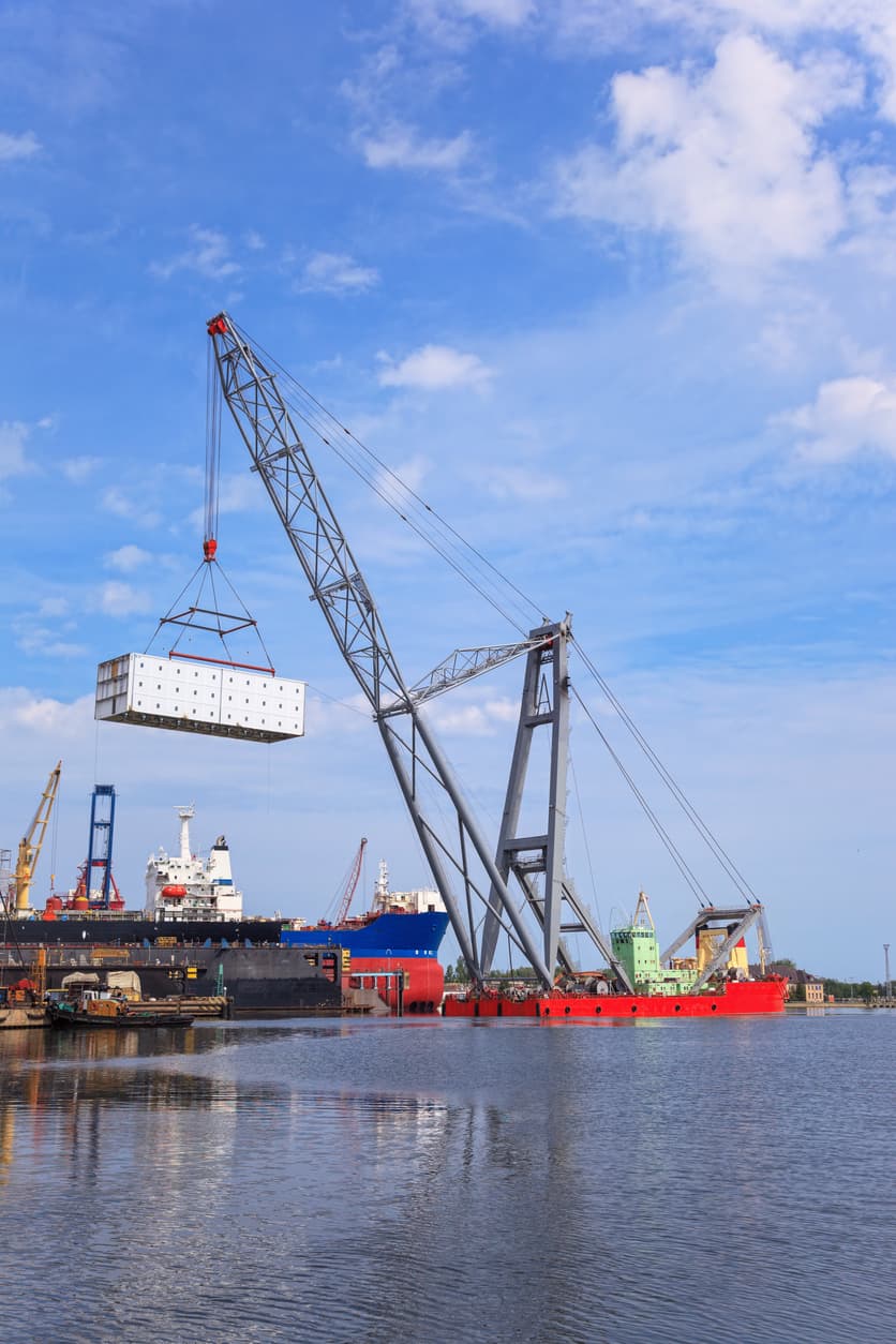 Floating crane barge lifting heavy module at port during coastal infrastructure construction